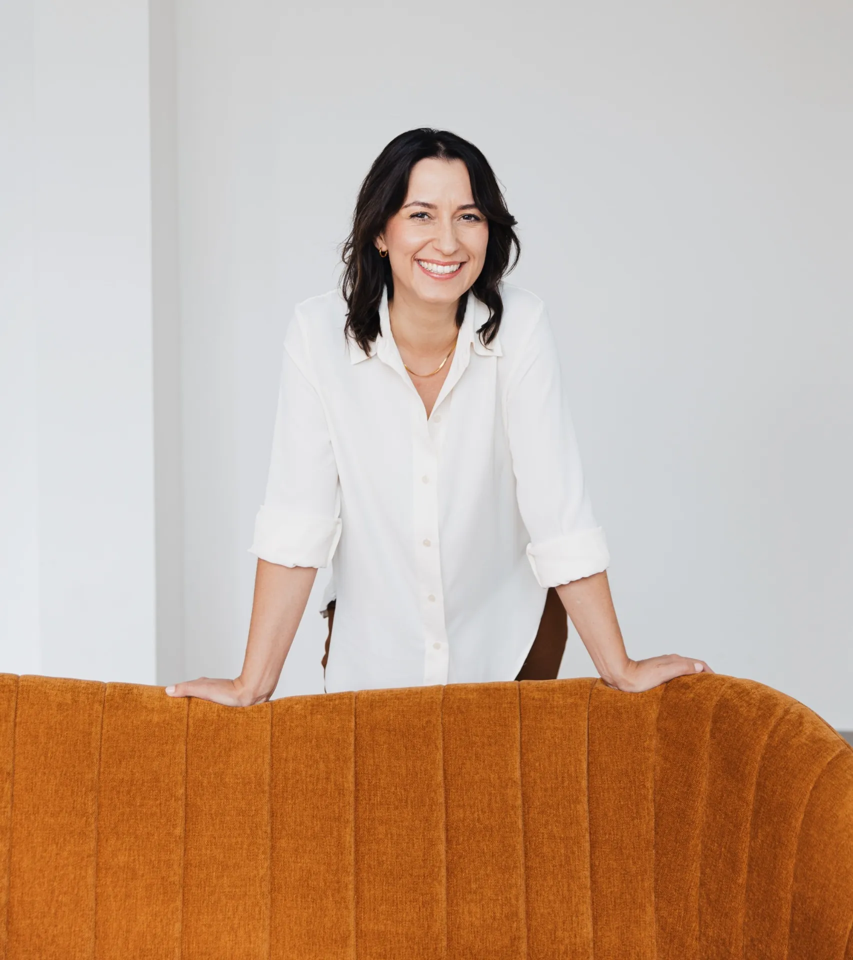 Madeleine Maßmann, zertifizierte Life Coachin, lächelnd stehend hinter einer ockerfarbenen Couch